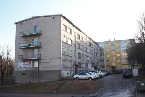 a tall brick building with cars parked in a parking lot at Siauliai Apartments - Ežero in Šiauliai