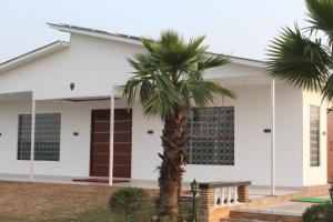 a palm tree in front of a white building at Luxe Farm in Greater Noida