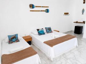 a white room with two beds and a table at Canto das Praieiras - Porto de Sauípe, Rio & Mar in Porto de Sauipe