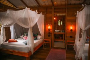 a bedroom with a canopy bed with curtains at Madre Selva Eco Lodge in Nuquí