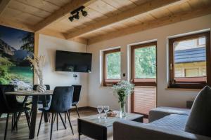 a living room with a table and chairs and windows at Domek Za Dworem in Witów