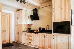 a kitchen with wooden cabinets and a black counter top at Domek Za Dworem in Witów