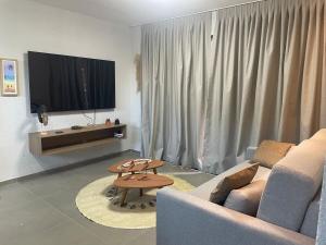 a living room with a couch and a tv at Villa Maui - Milagres in Passo de Camarajibe