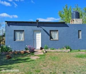 a blue house with a white door in a yard at Villarrica in Valle Hermoso