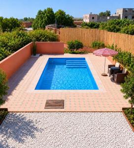 a small swimming pool on a patio with an umbrella at Quiet house with pool in Aïn Harrouda