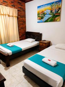 a room with two beds and a painting on the wall at Hotel Arauca Colonial in Arauca +8 photos