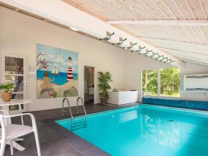 a swimming pool in a room with a table and chairs at 5 star holiday home in Bindslev in Bindslev