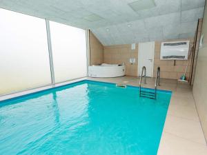 a large swimming pool with blue water in a room at Luxury Retreat in Vorupor in Snedsted