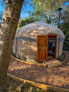 a large dome tent with a wooden door next to a tree at Cotswolds Camping at Holycombe in Shipston-on-Stour