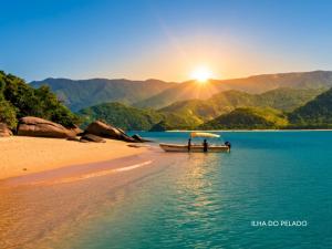 two people on a boat on a beach with the sunset at Pousada Caiçara Zen in Paraty