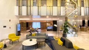 an office lobby with couches and tables and yellow chairs at voco Xian ETDZ by IHG in Xi'an