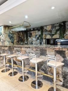 a bar with four chairs in front of a stone wall at Village Garden Apart Hotel in Buenos Aires