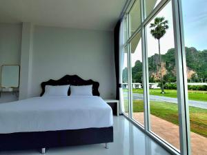 a bedroom with a bed and a large window at นัชชานามุงโฮมสเตย์ in Ban Mung