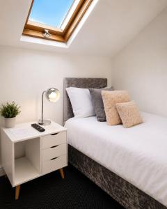 a bedroom with a bed with a nightstand and a window at Spacious Large Group House Near NEC and Airport in Birmingham