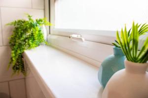 a window sill with a green vase and a plant at Spacious Large Group House Near NEC and Airport in Birmingham +22 photos