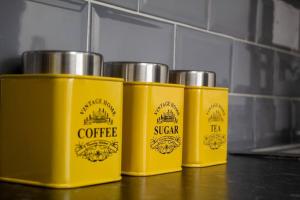 four yellow containers sitting on top of a counter at Spacious Large Group House Near NEC and Airport in Birmingham