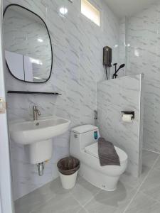 a bathroom with a sink and a toilet and a mirror at นัชชานามุงโฮมสเตย์ in Ban Mung