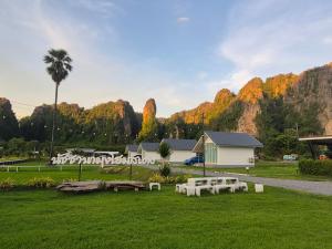 a park with benches and a palm tree and mountains at นัชชานามุงโฮมสเตย์ in Ban Mung
