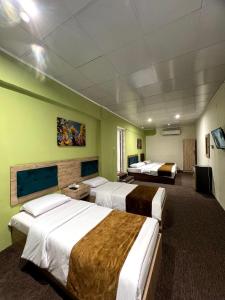 a hotel room with three beds and a tv at Modern Palace Dawassah in Al Mawşil
