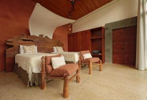 a bedroom with a large bed and two chairs at Origins Astral in Bagaces +32 photos