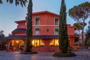 uma casa vermelha com duas árvores em frente em Resort La Rocchetta em La Giustiniana