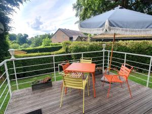 a deck with four chairs and a table and a fence at Sous les Hetres in Robertville