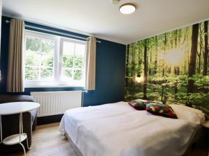 a bedroom with a bed with a wall mural of trees at Sous les Hetres in Robertville