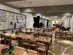 a restaurant with wooden tables and chairs with flowers at Elma Hotel and Art Complex in Zikhron Ya'akov