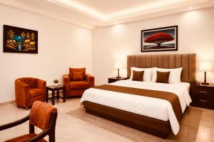 a bedroom with a large bed and a chair at E-Luxe Suites Hotel in Abuja