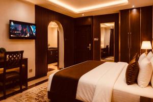 a hotel room with a bed and a tv at E-Luxe Suites Hotel in Abuja