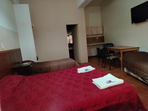 a bedroom with a red bed with two towels on it at Hotel Nerja in San Juan