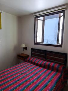 a bedroom with a bed with a striped bedspread and a window at La Chakana in Uspallata +14 photos
