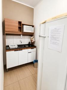 a kitchen with a white refrigerator and a microwave at Pousada Vale das Flores in Charqueadas
