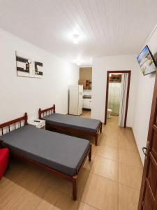 a room with two beds and a refrigerator at Pousada Vale das Flores in Charqueadas