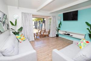 a living room with a white couch and a tv at Konoha Central 9BR, 3 Pools, Sleeps 24 in Avarua