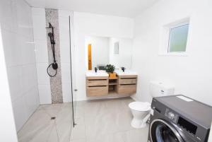 a bathroom with a toilet and a sink and a washing machine at Konoha Central 9BR, 3 Pools, Sleeps 24 in Avarua +27 photos