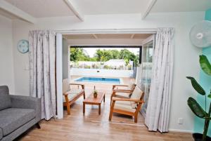 a living room with a couch and chairs and a pool at Konoha Central 9BR, 3 Pools, Sleeps 24 in Avarua