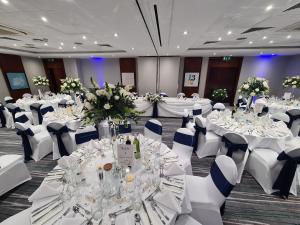 a banquet hall with white tables and white chairs at Holiday Inn London-Bexley by IHG in Bexley