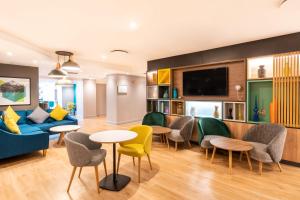 a living room with a couch and chairs and a tv at Holiday Inn London-Bexley by IHG in Bexley