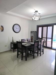a dining room with a table and chairs and a clock at Modern House with Private Pool in Santa Rosa de Copán