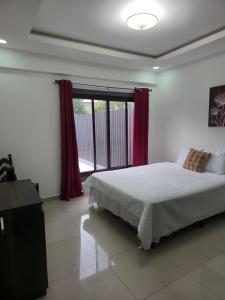 a bedroom with a bed and a window with red curtains at Modern House with Private Pool in Santa Rosa de Copán +21 photos