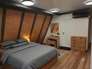 a bedroom with a large bed and a wooden wall at Breeze Cabin كوخ النسيم in Ilijaš