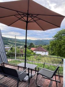 a table and chairs on a deck with an umbrella at Breeze Cabin كوخ النسيم in Ilijaš