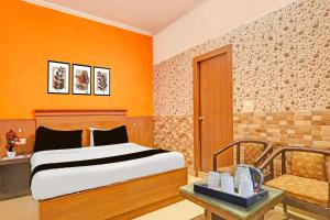 a bedroom with a bed with an orange wall at Super Hotel O Kanode Gate Formerly Hotel Dhruv in Rewāri