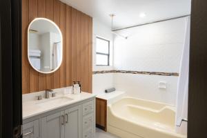 a bathroom with a sink and a tub and a mirror at Sunshine Lodge Inn in Gibsons