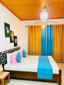 a bedroom with a large bed with colorful pillows at FEEL Villa in Kalutara