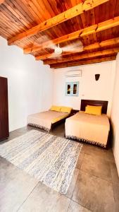 two beds in a room with a wooden ceiling at Wanasa house in Dahab