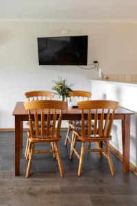 a wooden table with four chairs and a television at Bayview Cabins Kangaroo Island in American River