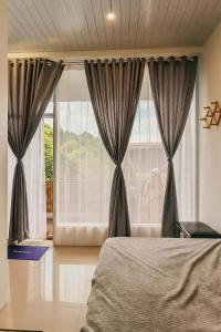 a bedroom with a bed and a large window at Sarasutha hotel and pool in Lembuak