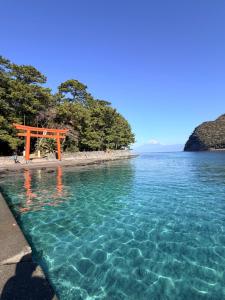 an orange torii gate on a beach near the water at Calmbase西伊豆いざよい in Numazu